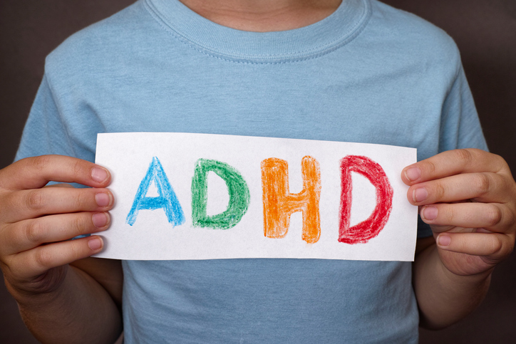 Момче държи табела с цветен надпис ADHD